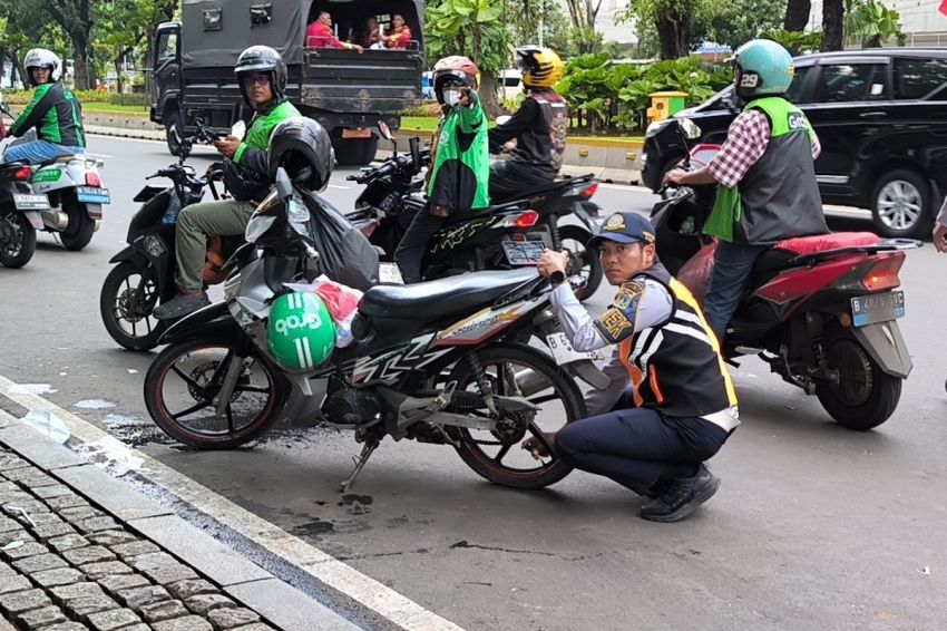 Petugas Dishub Kempiskan Ban Motor Ojol yang Parkir Sembarangan di Jalan Medan Merdeka